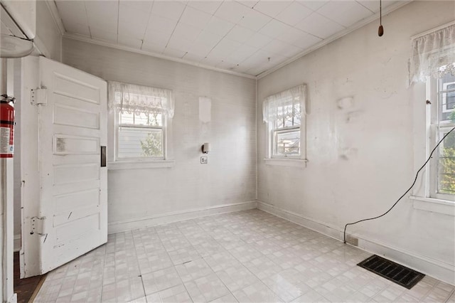 unfurnished room featuring visible vents, ornamental molding, and a wealth of natural light
