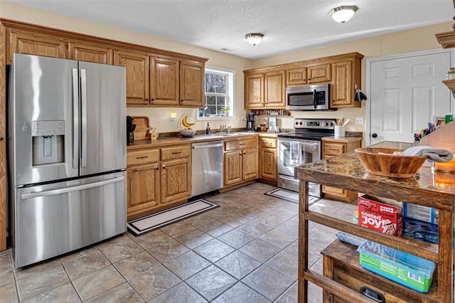 204 Lynn St, Lathrop, MO 64465 - kitchen with stainless steel appliances, a textured ceiling, a sink, and brown cabinetry