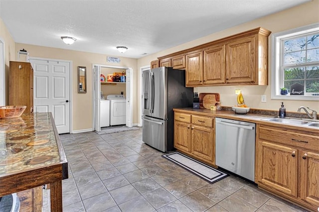 204 Lynn St, Lathrop, MO 64465 - kitchen featuring stainless steel appliances, a sink, washer and clothes dryer, a textured ceiling, and brown cabinets