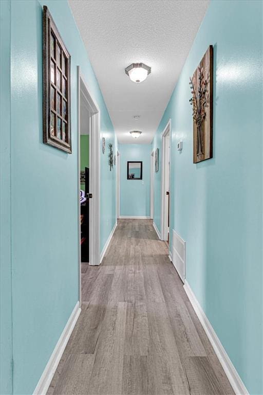 204 Lynn St, Lathrop, MO 64465 - hall featuring wood finished floors, baseboards, and a textured ceiling