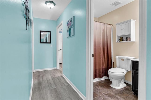 204 Lynn St, Lathrop, MO 64465 - full bathroom featuring toilet, baseboards, curtained shower, and vanity