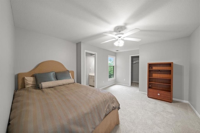 bedroom with a ceiling fan, baseboards, light colored carpet, and a walk in closet