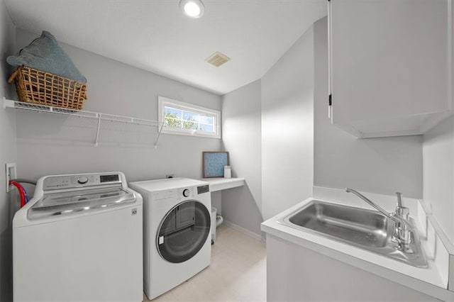 washroom featuring laundry area, visible vents, washing machine and dryer, a sink, and baseboards