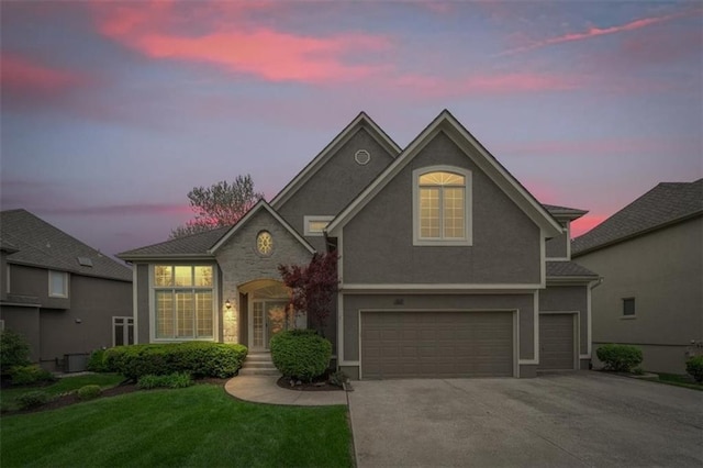 traditional-style house with a lawn, a garage, stucco siding, and driveway