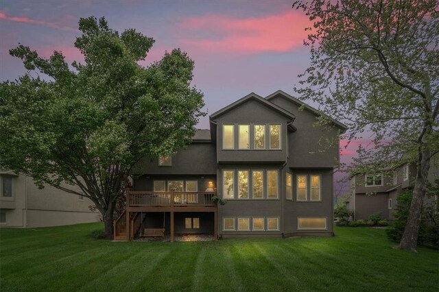 rear view of house featuring a lawn, stucco siding, stairs, and a deck