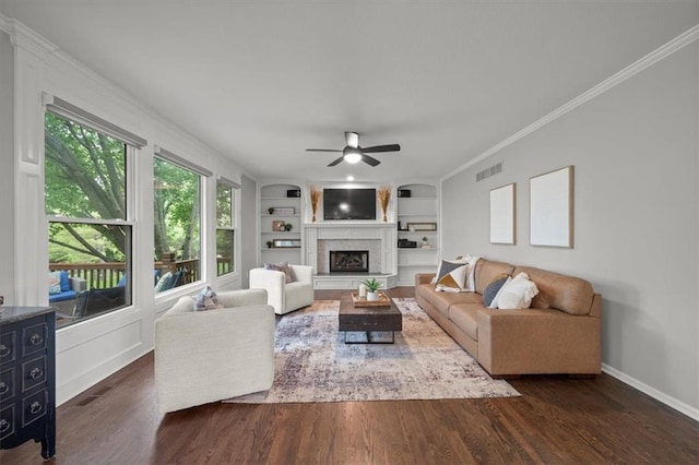 living area featuring visible vents, baseboards, a fireplace with raised hearth, a ceiling fan, and dark wood finished floors