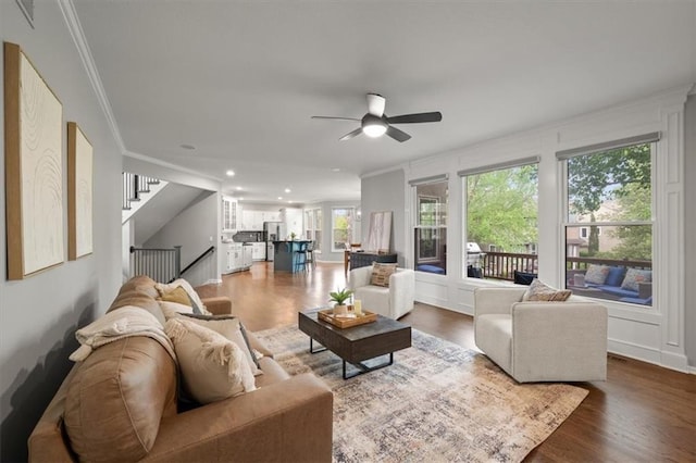 living room featuring crown molding, ceiling fan, stairs, and wood finished floors