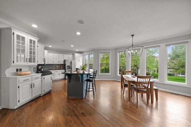 kitchen featuring a breakfast bar area, dark wood-style flooring, stainless steel fridge with ice dispenser, a chandelier, and recessed lighting