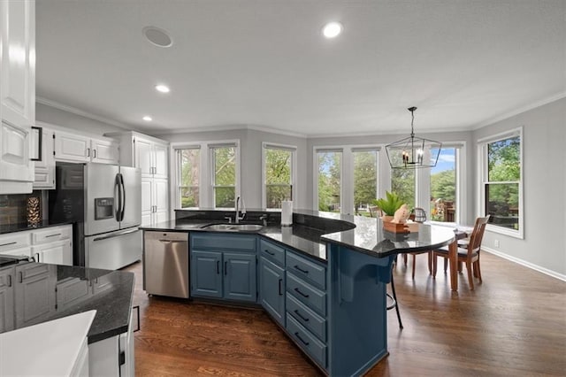 kitchen with crown molding, white cabinets, a sink, a wealth of natural light, and stainless steel appliances