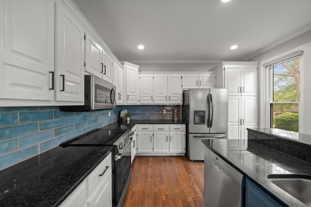 kitchen featuring white cabinets, stainless steel appliances, and ornamental molding