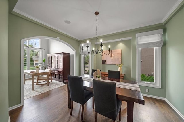 dining space featuring crown molding, a chandelier, and dark wood finished floors