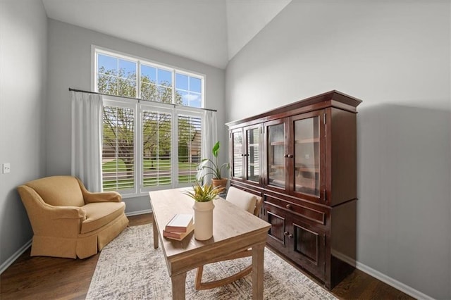 living area featuring high vaulted ceiling, baseboards, and wood finished floors