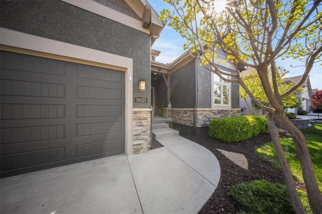view of home's exterior featuring a garage, stucco siding, driveway, and stone siding