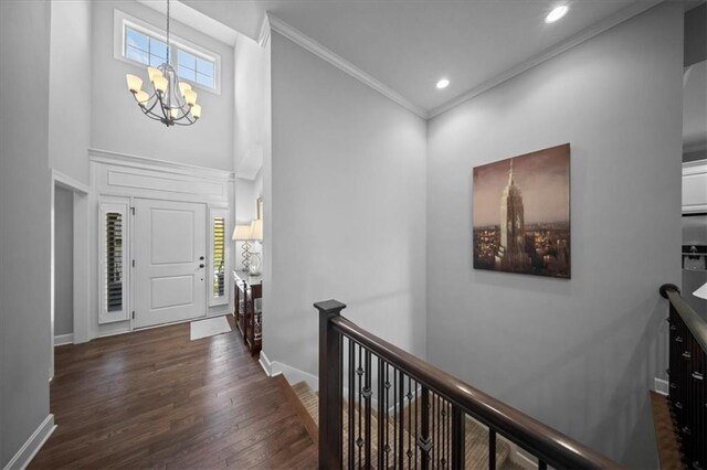 foyer with a high ceiling, a chandelier, a healthy amount of sunlight, and wood finished floors