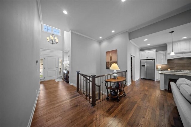 entryway with an inviting chandelier, crown molding, baseboards, recessed lighting, and dark wood finished floors