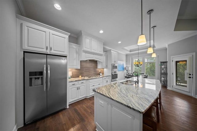 kitchen featuring decorative backsplash, appliances with stainless steel finishes, a sink, ornamental molding, and an island with sink