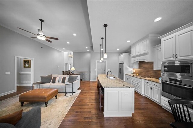 kitchen featuring appliances with stainless steel finishes, decorative backsplash, a ceiling fan, and open floor plan
