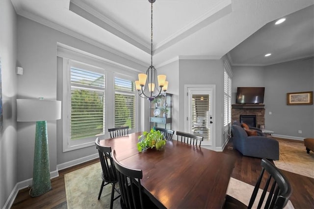 dining room with a fireplace, a chandelier, ornamental molding, baseboards, and dark wood-style floors