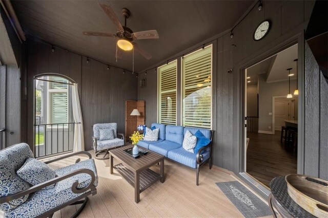 living room featuring crown molding, a ceiling fan, wood walls, and light wood-type flooring