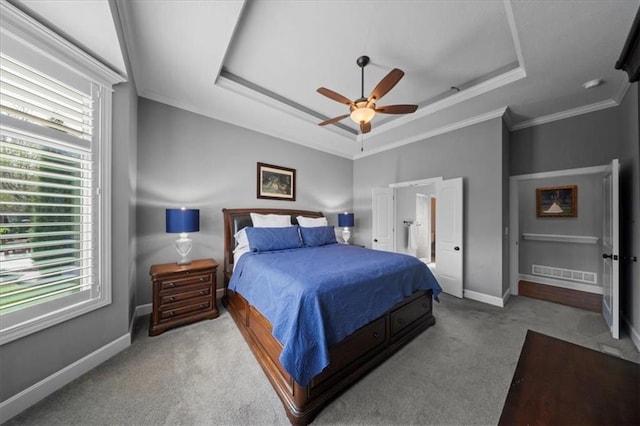 bedroom with crown molding, carpet flooring, a tray ceiling, and multiple windows