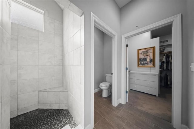 bathroom with toilet, visible vents, a walk in closet, and a stall shower