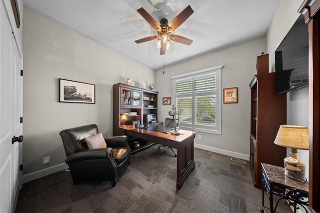 home office featuring dark carpet, a ceiling fan, baseboards, and visible vents