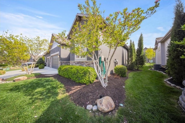 view of home's exterior featuring a yard, an attached garage, cooling unit, and stone siding