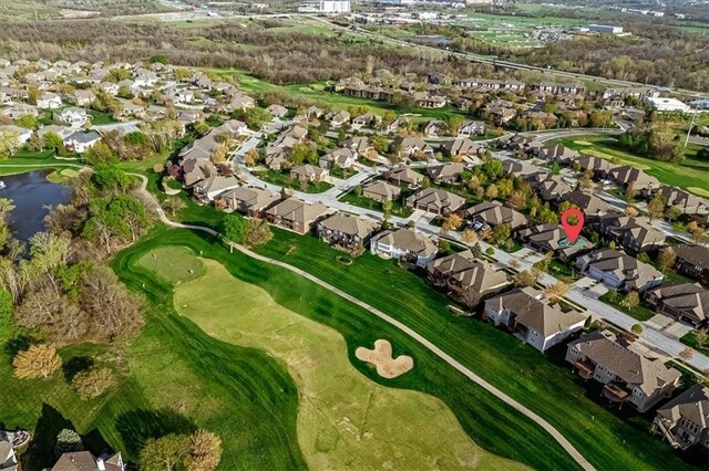 drone / aerial view with a water view, view of golf course, and a residential view
