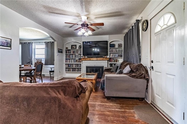 401 E Jackson St, Windsor, MO 65360 - living room with wood finished floors, a textured ceiling, ceiling fan, arched walkways, and a fireplace