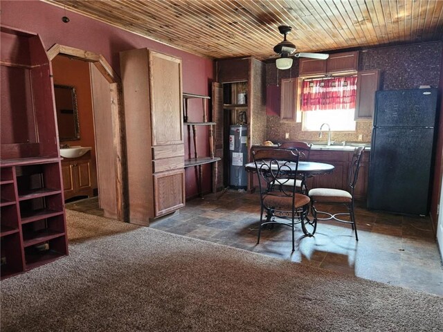 kitchen with water heater, freestanding refrigerator, wood ceiling, and a sink