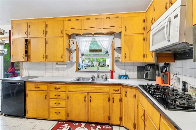 kitchen with decorative backsplash, a sink, light tile patterned floors, light countertops, and black appliances