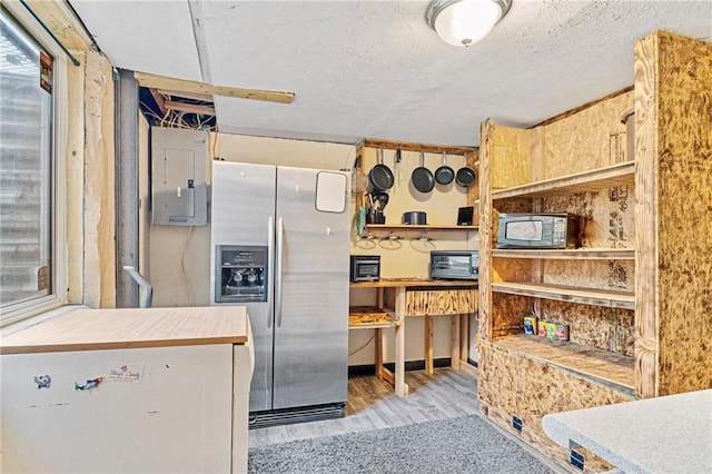 kitchen featuring wood finished floors, a toaster, a textured ceiling, electric panel, and stainless steel fridge with ice dispenser