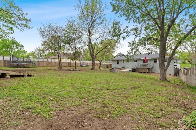 view of yard with a fenced backyard, a trampoline, and a wooden deck