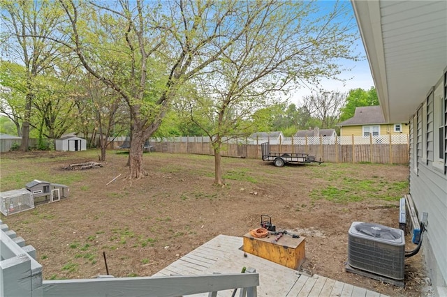 view of yard featuring a storage unit, a fenced backyard, central air condition unit, and an outdoor structure