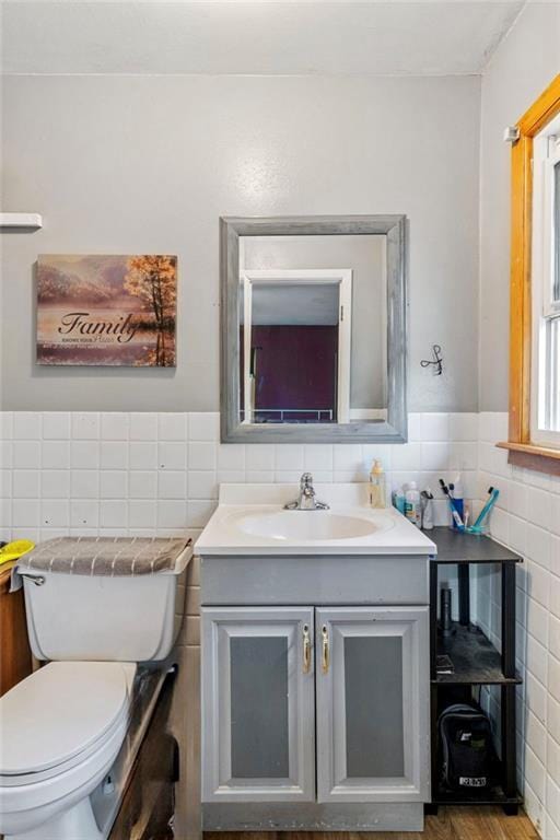 half bath featuring toilet, tile walls, and vanity