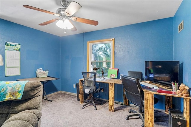 carpeted office featuring a ceiling fan, a textured wall, and visible vents