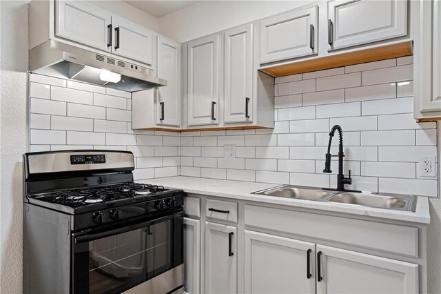 kitchen with stainless steel range with gas cooktop, a sink, under cabinet range hood, and tasteful backsplash