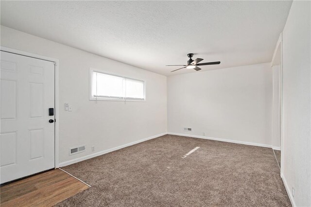interior space featuring carpet flooring, ceiling fan, a textured ceiling, baseboards, and visible vents