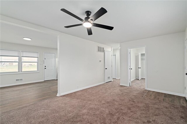 interior space featuring baseboards, a ceiling fan, wood finished floors, and visible vents