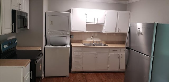 8508 Ruskin Way, Kansas City, MO 64134 - kitchen with stainless steel appliances, stacked washer / drying machine, crown molding, white cabinetry, and light countertops