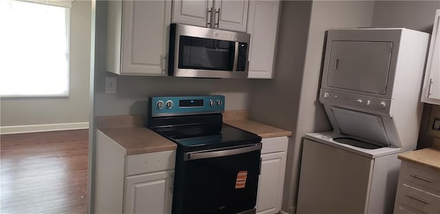 8508 Ruskin Way, Kansas City, MO 64134 - kitchen with electric range, stainless steel microwave, stacked washer and clothes dryer, light countertops, and healthy amount of natural light