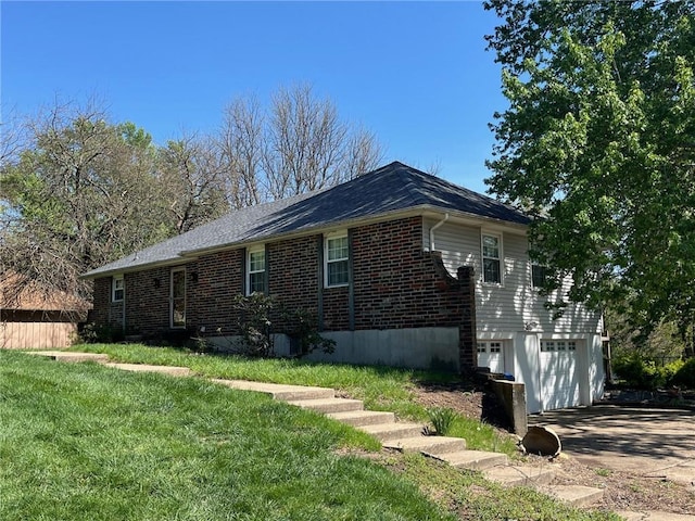 view of side of home with concrete driveway, brick siding, an attached garage, and a yard