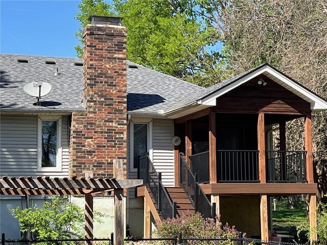 view of front of property with a shingled roof, a chimney, and fence private yard