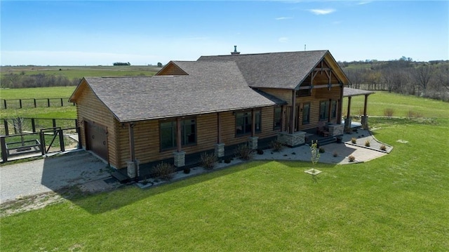 back of property with a garage, a shingled roof, fence, and a yard