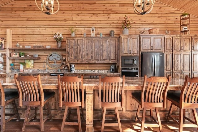 kitchen featuring freestanding refrigerator, dark countertops, oven, wooden walls, and built in microwave