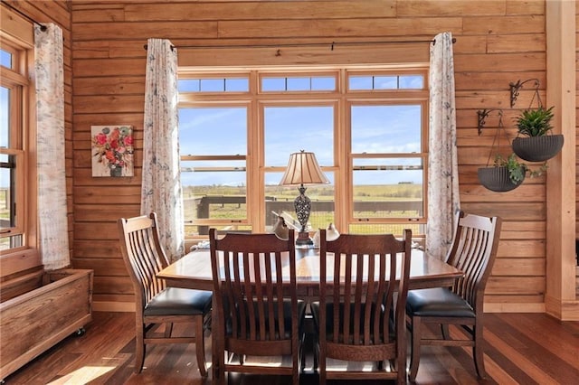 dining room with a healthy amount of sunlight, wood walls, and wood finished floors