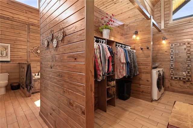 bathroom featuring washing machine and dryer, wood walls, and wood finished floors