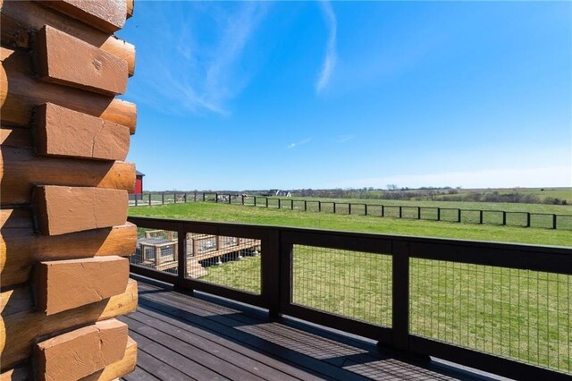 wooden terrace featuring a lawn, a rural view, and fence