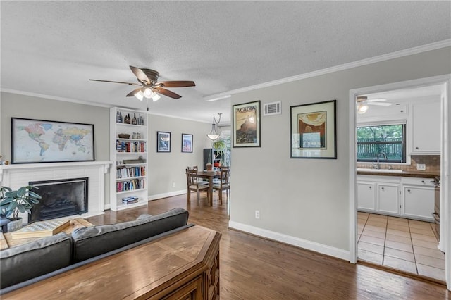 living area featuring crown molding, ceiling fan, and visible vents