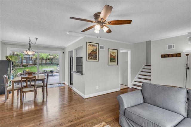 living area with visible vents, ornamental molding, a ceiling fan, and wood finished floors